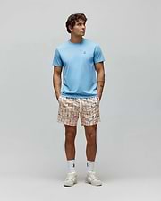 Light blue Mens Classic Crew Neck Tee, classic fit jersey, with small embroidered Psycho Bunny skull logo. Paired with cream relaxed fit shorts, vibrant multi-color grid pattern, and integrated bunny skull logos.