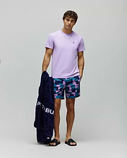 Mens Classic Crew Neck Tee, a classic fit lavender jersey t-shirt with an embroidered chest Psycho Bunny logo, paired with relaxed geometric print swim shorts in navy, teal, and purple.