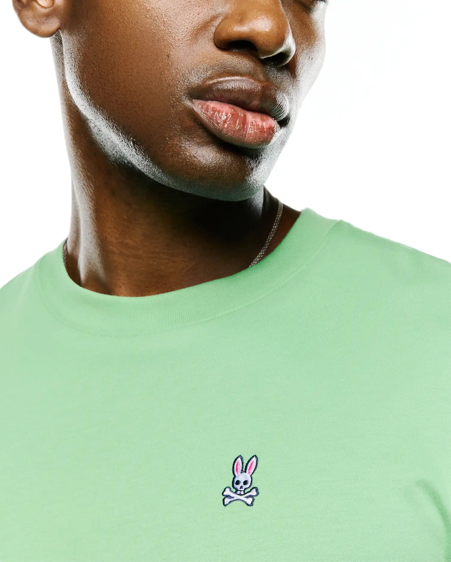 Men's Classic Pima Crew Neck Tee in light green, featuring a smooth jersey texture and a small, embroidered Psycho Bunny skull logo with pink ears on the left chest.