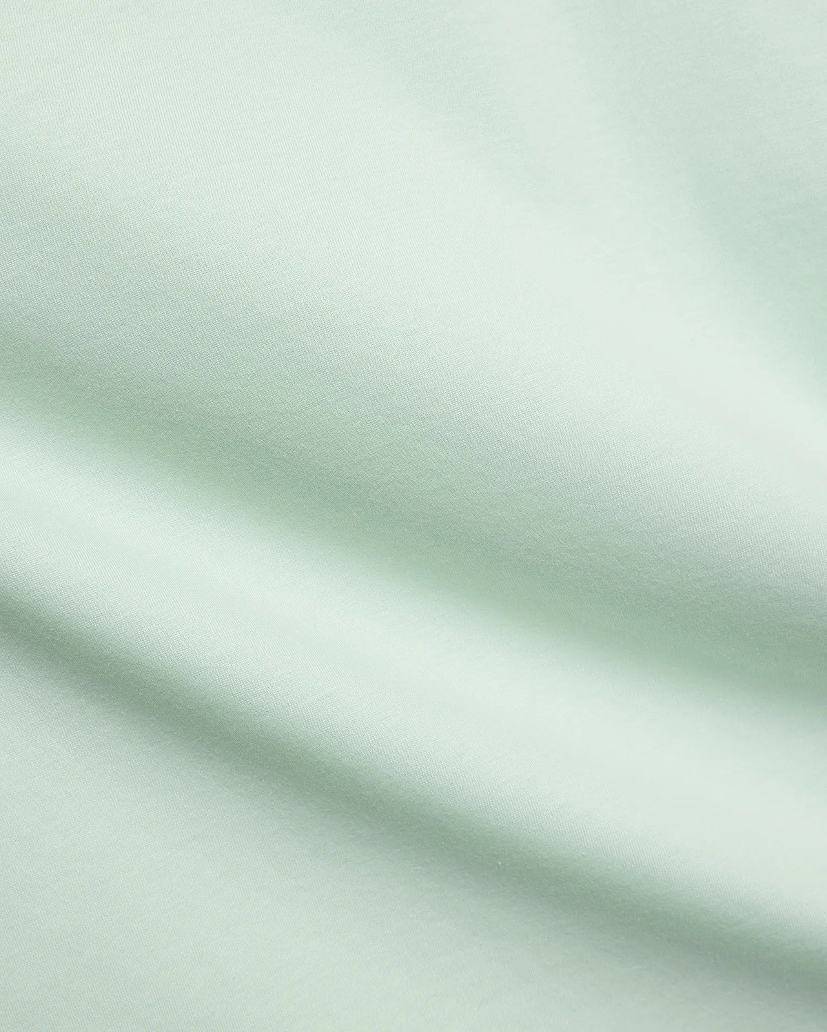 Mens Classic Crew Neck Tee in a premium, soft pale mint green jersey fabric, showcasing a smooth, refined texture with subtle diagonal knit details, characteristic of Psycho Bunny's elevated streetwear.