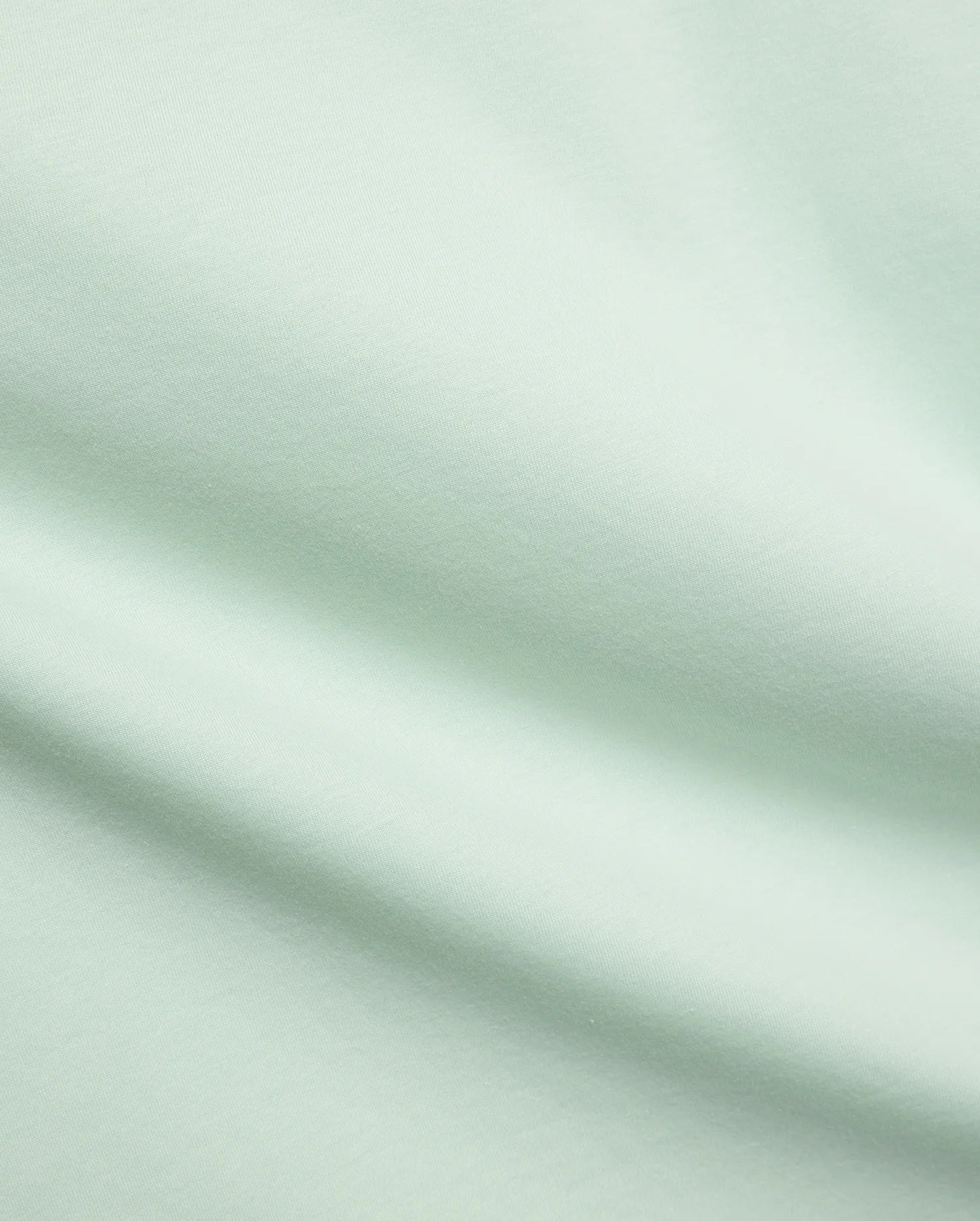 Mens Classic Crew Neck Tee in a premium, soft pale mint green jersey fabric, showcasing a smooth, refined texture with subtle diagonal knit details, characteristic of Psycho Bunny's elevated streetwear.