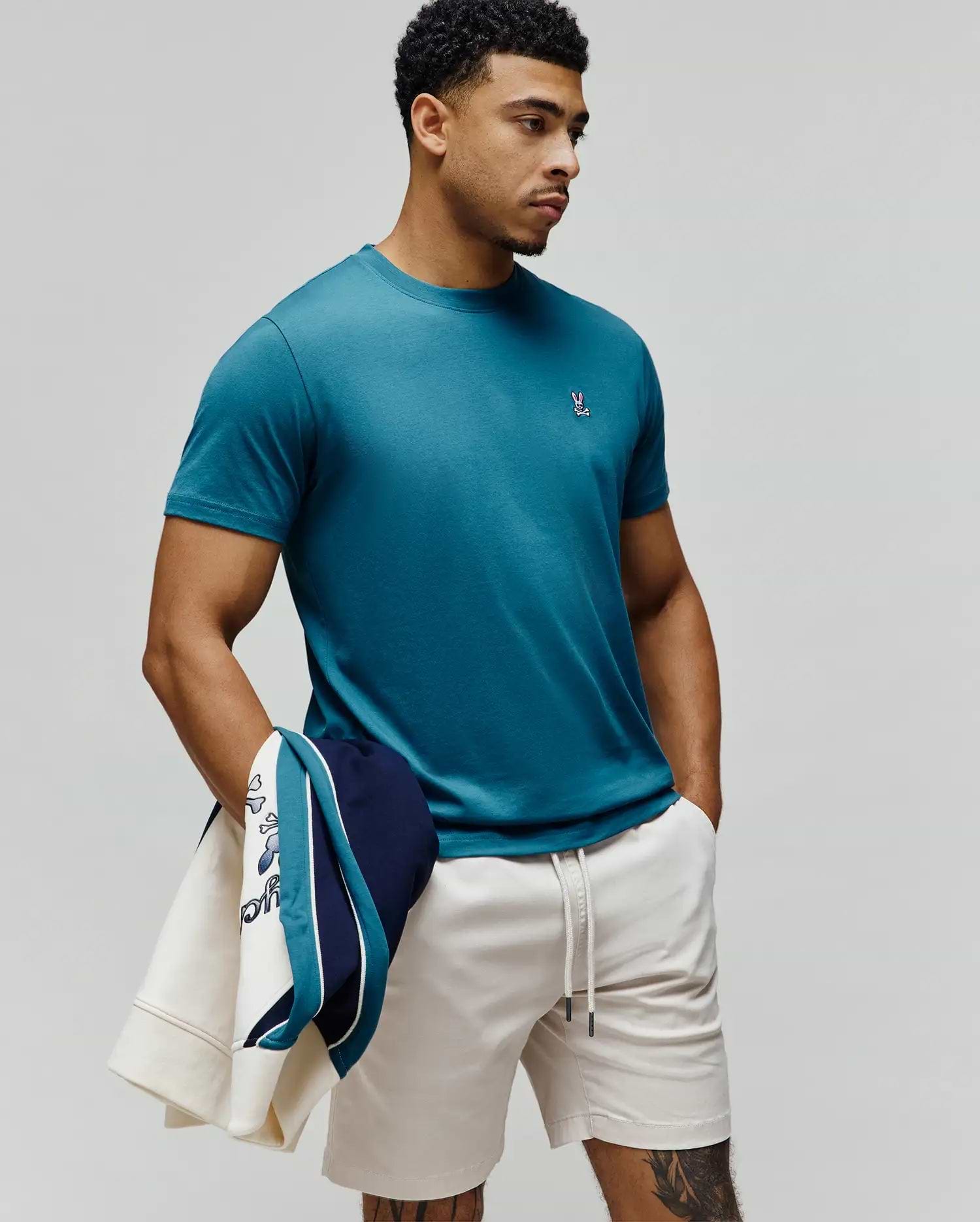 Mens Classic Crew Neck Tee in rich teal, featuring a classic fit and smooth jersey knit. A small, embroidered Psycho Bunny skull logo with pink, white, and black accents is on the left chest.