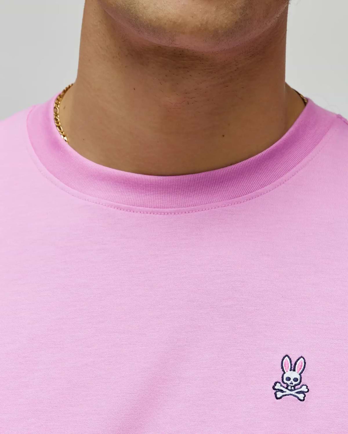 Mens Classic Crew Neck Tee in vibrant pink jersey knit, featuring a classic fit and a small, intricately embroidered Psycho Bunny skull logo on the left chest with white and black details.
