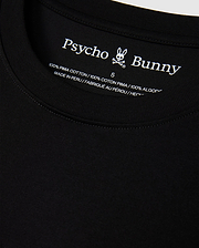 Close-up of the MENS HAWAII CITY TEE by Psycho Bunny, highlighting the black label inside the collar featuring its iconic logo and text indicating it's crafted from 100% Pima cotton, made in Peru.