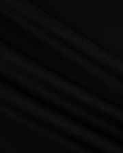A close-up image of the MENS NEW YORK TEE - B6U554W1PC by Psycho Bunny showcases its smooth, black Pima cotton fabric with soft, diagonal folds. The material has a slightly matte texture and appears to be lightweight. The folds create subtle shadows and highlights, adding depth to the otherwise uniform color. A small Bunny logo is visible in the corner.