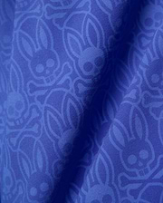 Mens Samos Hydrochromic Printed Swim Trunk in royal blue, featuring a subtle tonal all-over Psycho Bunny skull and crossbones logo pattern on smooth fabric.