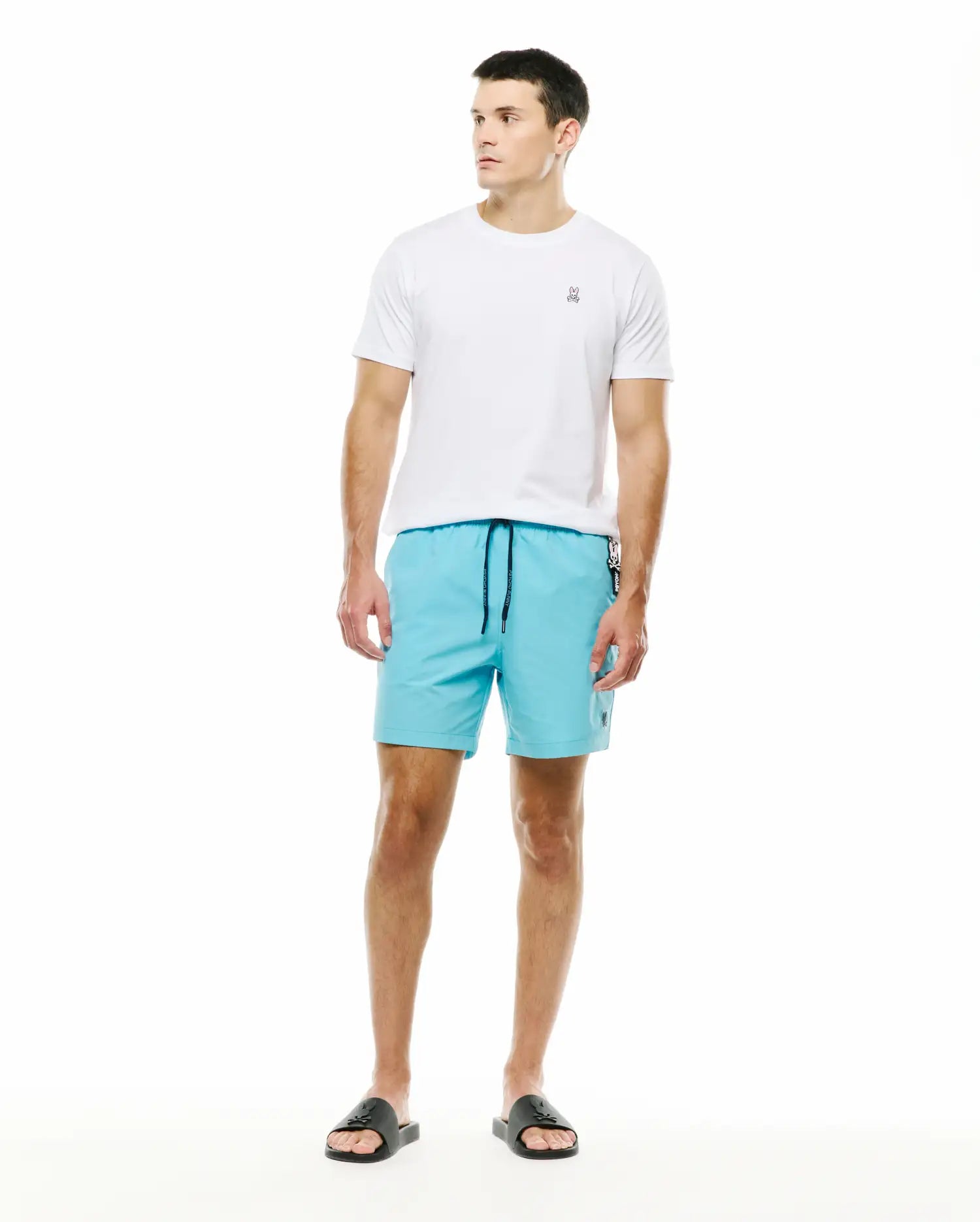 Mens Samos Hydrochromic Swim Trunks in aqua blue, featuring a black drawstring and small embroidered Psycho Bunny logo, complemented by a classic fit white jersey t-shirt with a small embroidered skull on the left chest. (5)