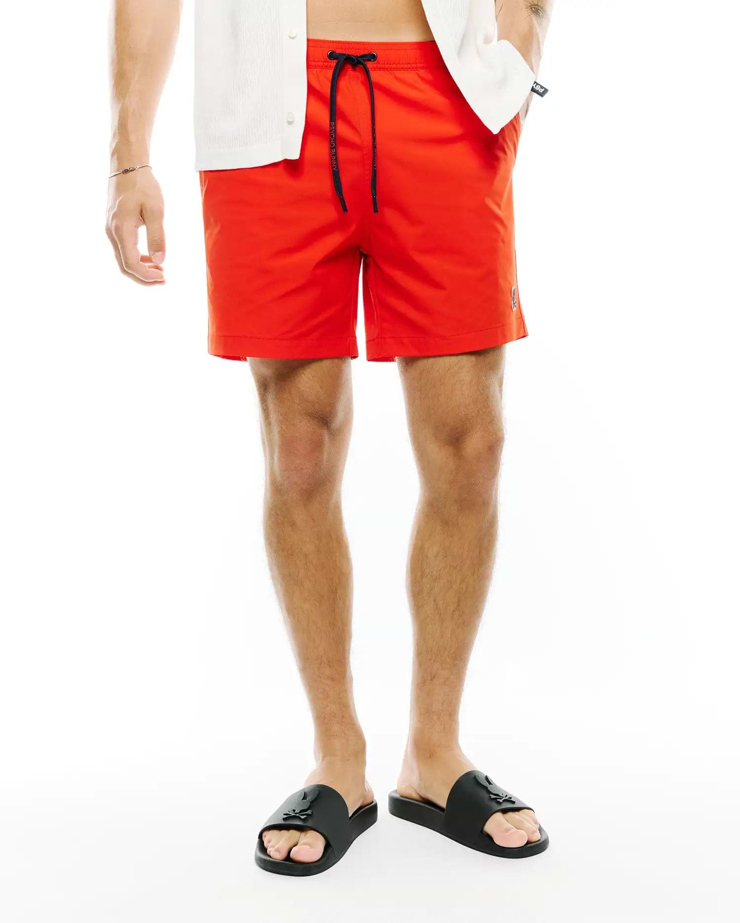 Vibrant Red Mens Samos Hydrochromic Printed Swim Trunk, featuring a relaxed fit, smooth quick-dry fabric, black drawstring with Psycho Bunny text, and a small embroidered bunny skull logo on the lower left leg.