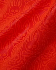 Mens Samos Hydrochromic Printed Swim Trunk in vibrant red, featuring a subtle tonal allover Psycho Bunny skull and crossbones pattern on smooth, slightly textured fabric.