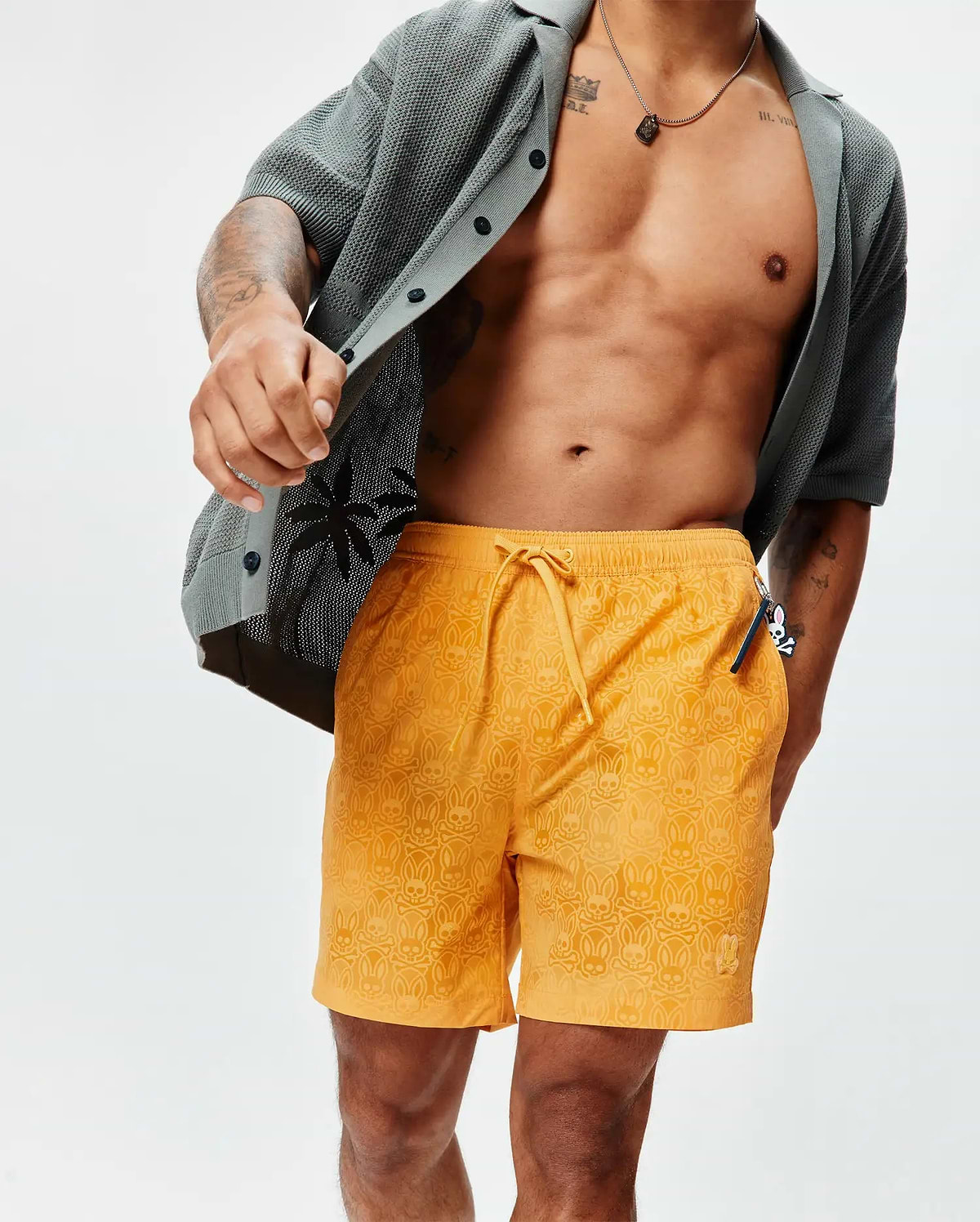 Mens Samos Hydrochromic Printed Swim Trunk in vibrant orange, featuring an all-over subtle hydrochromic Psycho Bunny skull and crossbones print, drawstring waist, and small embroidered bunny logo on the left leg, offering a relaxed fit. (3)