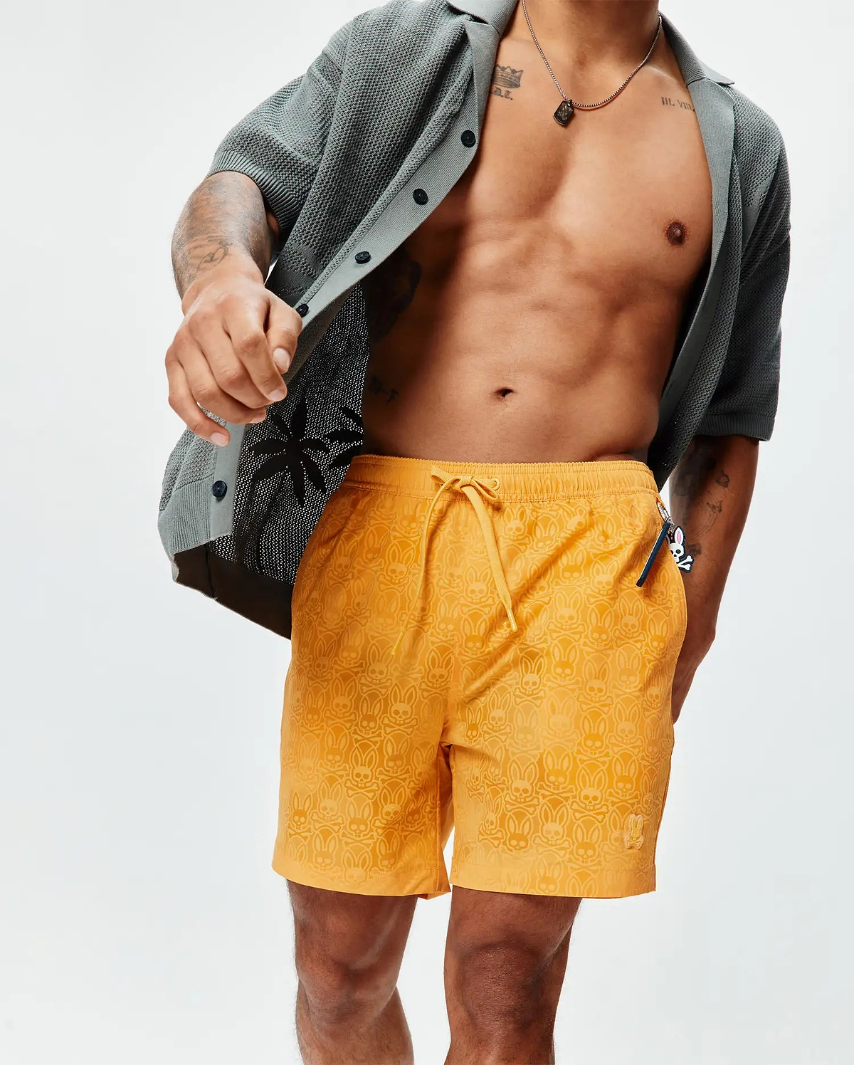 Mens Samos Hydrochromic Printed Swim Trunk in vibrant orange, featuring an all-over subtle hydrochromic Psycho Bunny skull and crossbones print, drawstring waist, and small embroidered bunny logo on the left leg, offering a relaxed fit. (3)