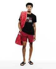 Black jersey t-shirt with large red, white, and black Psycho Bunny skull graphic on chest, paired with Mens Samos Hydrochromic Printed Swim Trunk in maroon with a small white logo, and a red patterned terry towel.