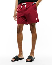Samos Hydrochromic Printed Swim Trunk in deep red, featuring a relaxed fit, smooth quick-dry fabric, white drawstring, small embroidered white Psycho Bunny skull logo on the left leg, and a black Psycho Bunny tag on the right pocket.