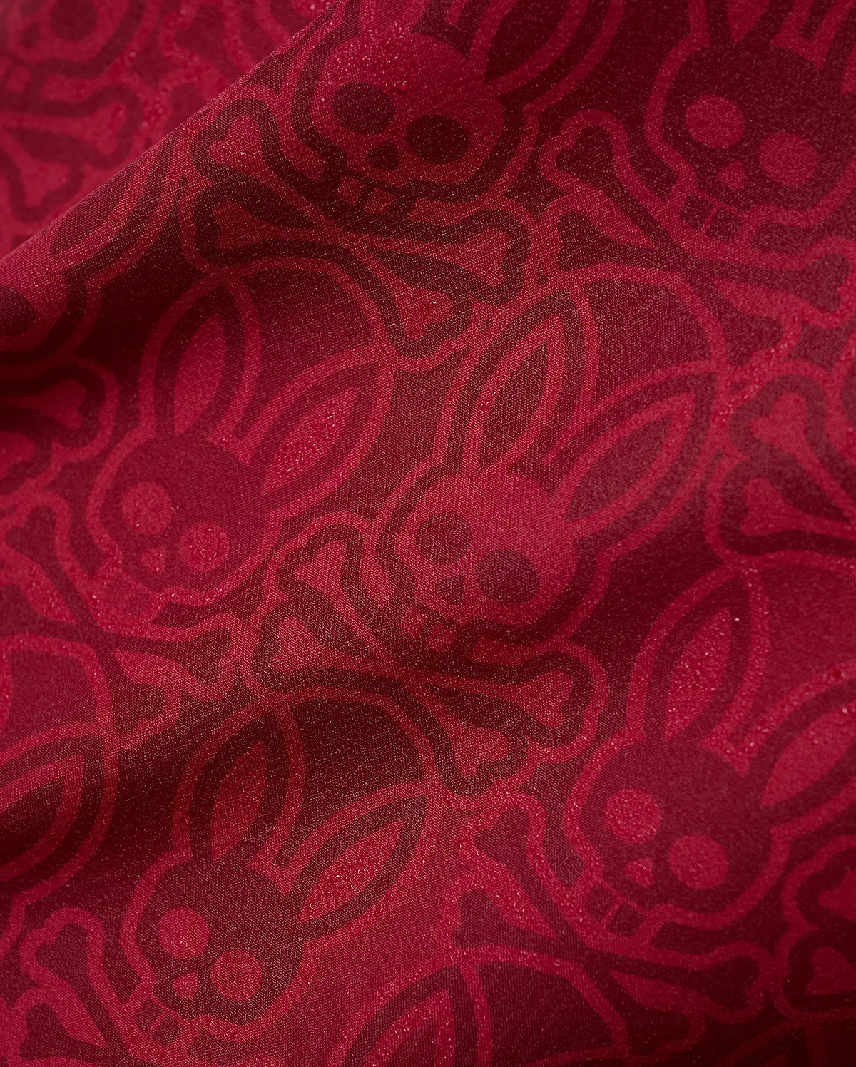 Mens Samos Hydrochromic Printed Swim Trunk in rich red, featuring an all-over darker red hydrochromic Psycho Bunny skull and crossbones pattern on smooth fabric.