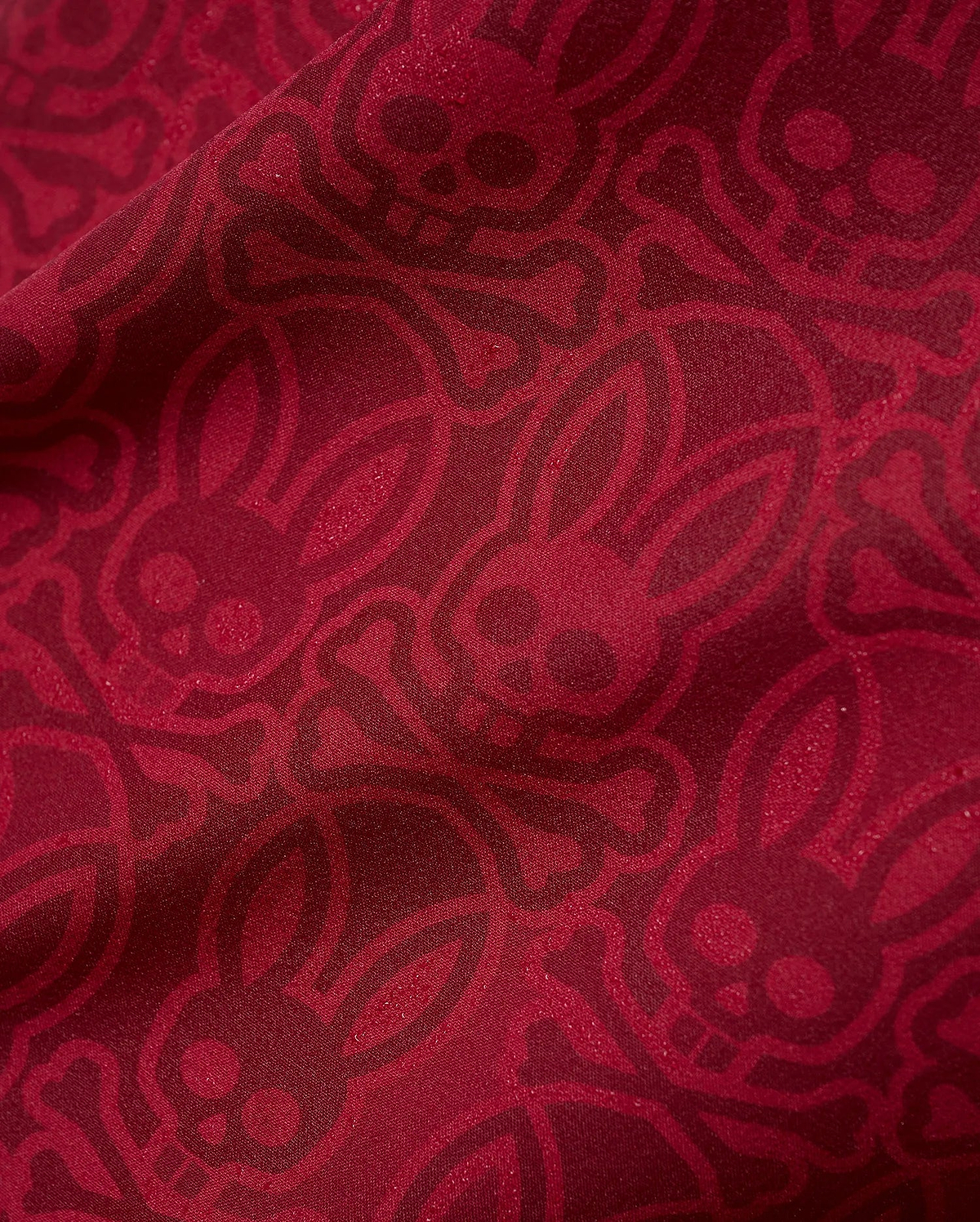 Mens Samos Hydrochromic Printed Swim Trunk in rich red, featuring an all-over darker red hydrochromic Psycho Bunny skull and crossbones pattern on smooth fabric.