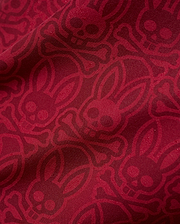 Mens Samos Hydrochromic Printed Swim Trunk in rich red, featuring an all-over darker red hydrochromic Psycho Bunny skull and crossbones pattern on smooth fabric.