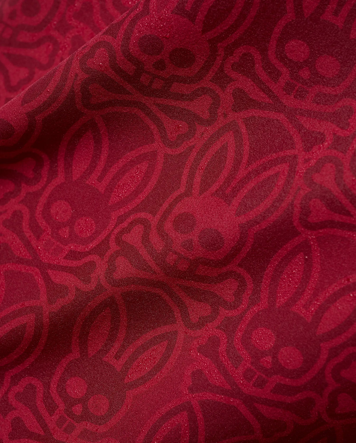 Mens Samos Hydrochromic Printed Swim Trunk in rich red, featuring an all-over darker red hydrochromic Psycho Bunny skull and crossbones pattern on smooth fabric.