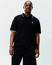 Black Big And Tall Sunny Pique Polo, classic fit, pique knit, with white and light blue tipping on collar and sleeve cuffs, and a small embroidered white Psycho Bunny skull logo on the left chest.