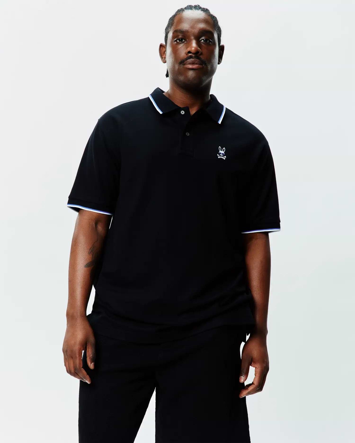 Black Big And Tall Sunny Pique Polo, classic fit, pique knit, with white and light blue tipping on collar and sleeve cuffs, and a small embroidered white Psycho Bunny skull logo on the left chest.