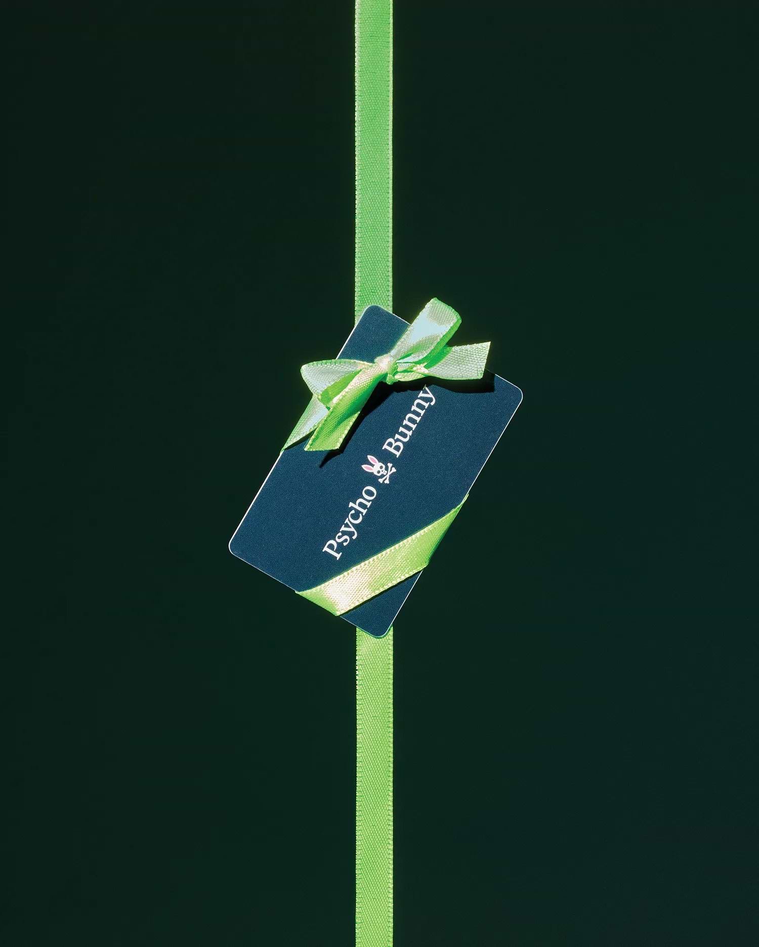 Psycho Bunny Digital Gift Card, a dark blue card featuring the iconic white bunny skull logo and brand name, elegantly wrapped with a vibrant lime green ribbon and bow.