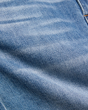 Kids Emerson Denim Pant featuring a classic medium blue washed denim with a prominent twill weave texture, natural fading, and subtle creasing, accented by visible warm brown stitching.