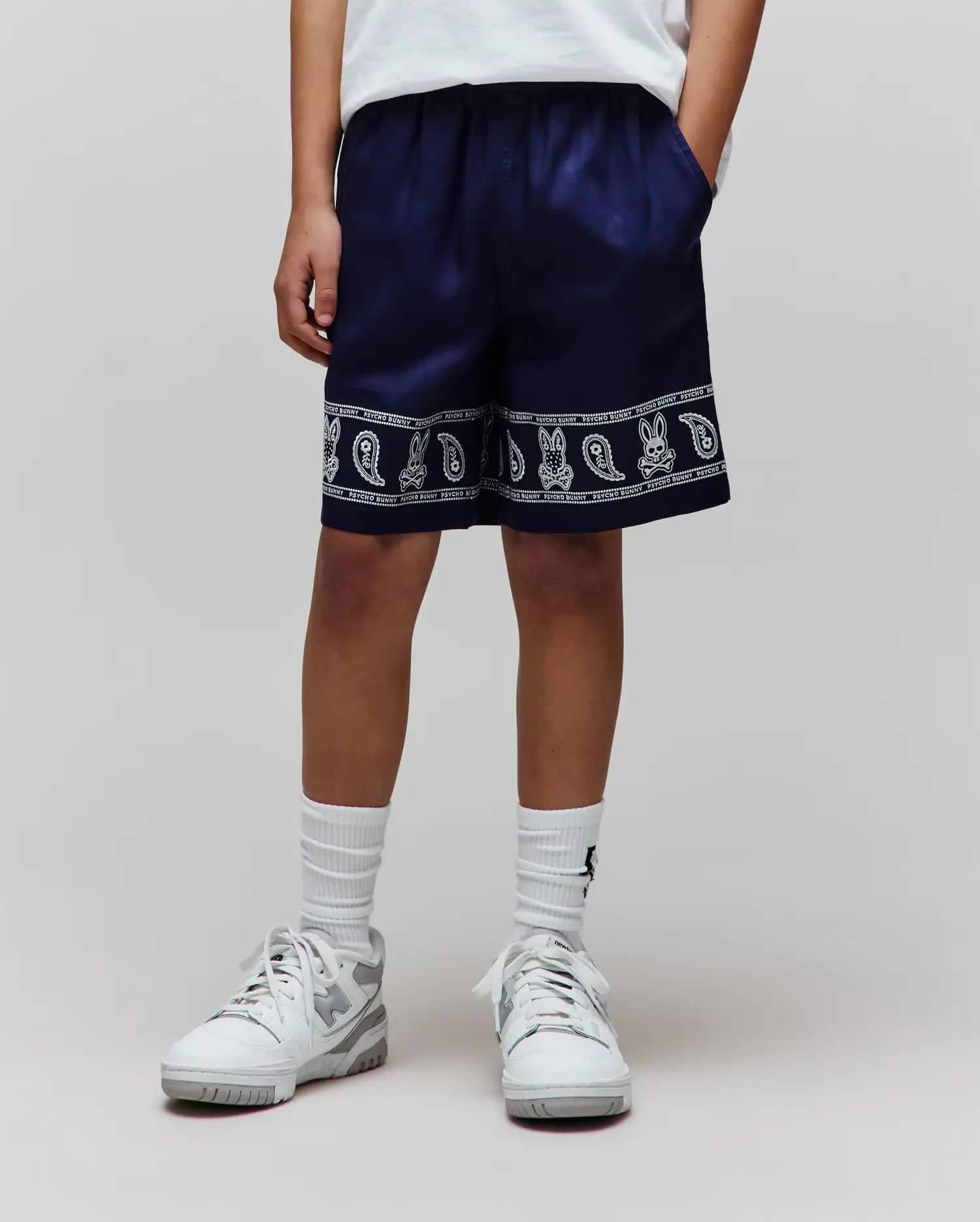 Kids Luke Tencel Short, navy relaxed-fit shorts with a white bandana-style print featuring repeated Psycho Bunny skull logos and paisley patterns along the hem, bordered by Psycho Bunny text.