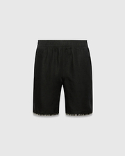 Kids Brad Linen Short, black relaxed fit with linen texture, featuring a subtle tonal embroidered Psycho Bunny skull logo on the lower right leg and white contrast blanket stitching on the hem.