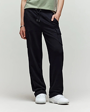 A child models Psycho Bunny’s KIDS NASH CARGO SWEATPANT - KB0800004 in green, showcasing utility cargo pockets and sweatpant comfort, with only the lower half and white sneakers visible against a plain light background.