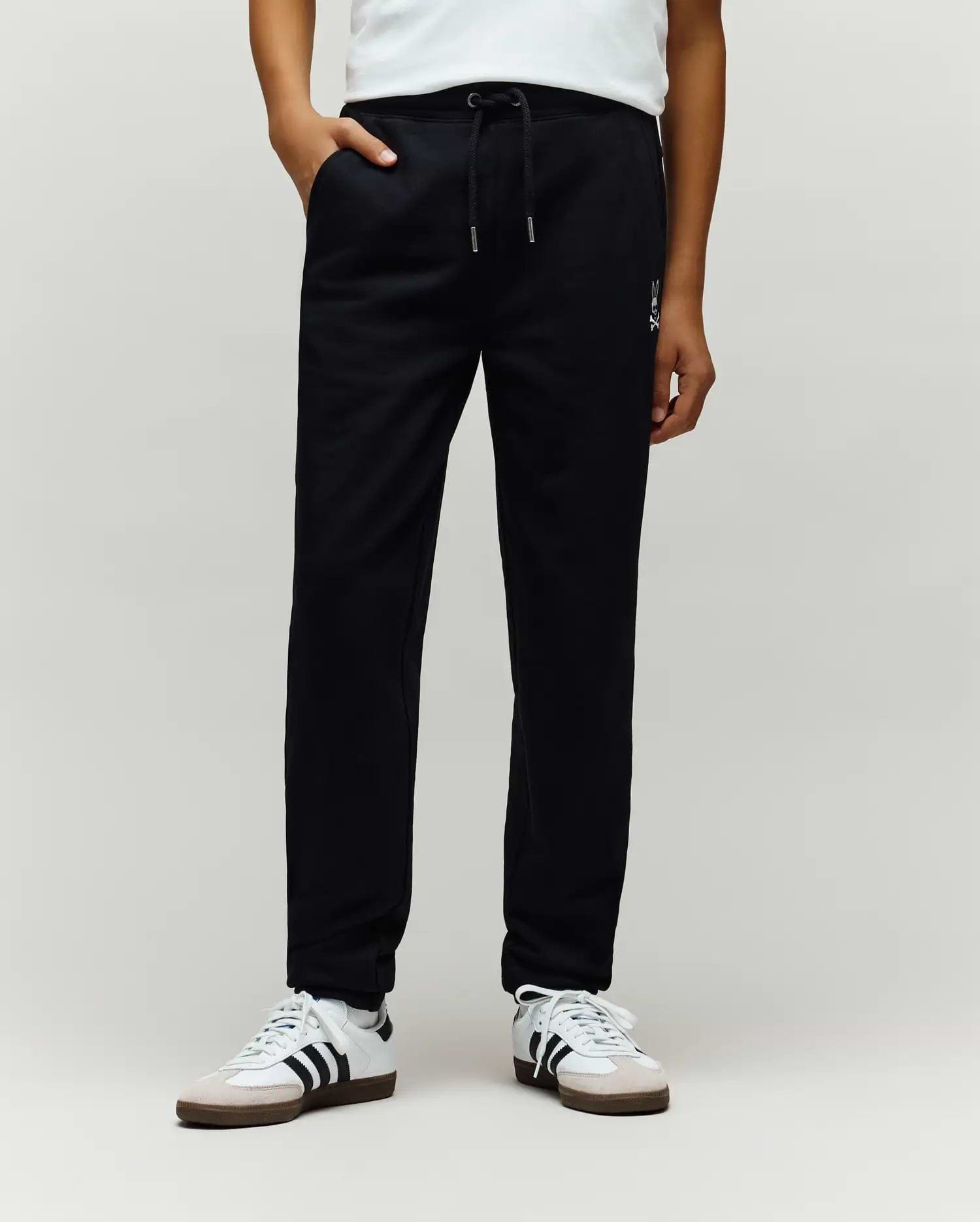 Kids Timothy 4k Bunny Jogger in black smooth jersey, featuring a relaxed fit, drawstring waist, side pockets, and a small white embroidered Psycho Bunny skull logo on the left thigh.