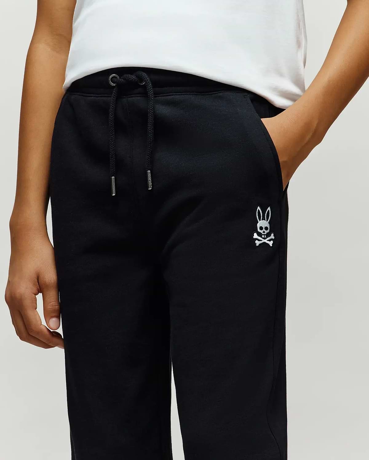 Kids Timothy 4k Bunny Jogger in black french terry, featuring a relaxed fit, drawstring waist with silver tips, and a small white embroidered Psycho Bunny skull logo on the left thigh.