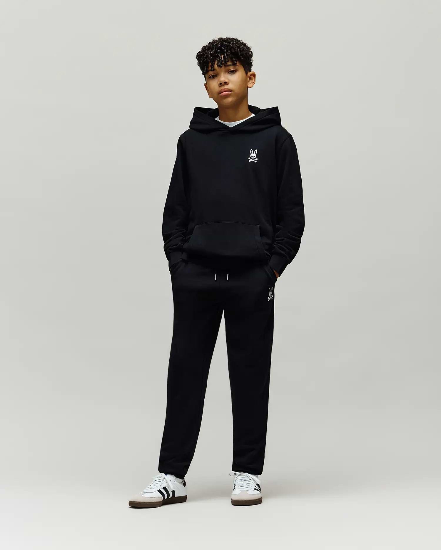 Black Kids Timothy 4k Bunny Jogger and matching hoodie, both featuring a small white embroidered Psycho Bunny skull logo on the left chest and left thigh, in a relaxed fit soft French terry fabric.