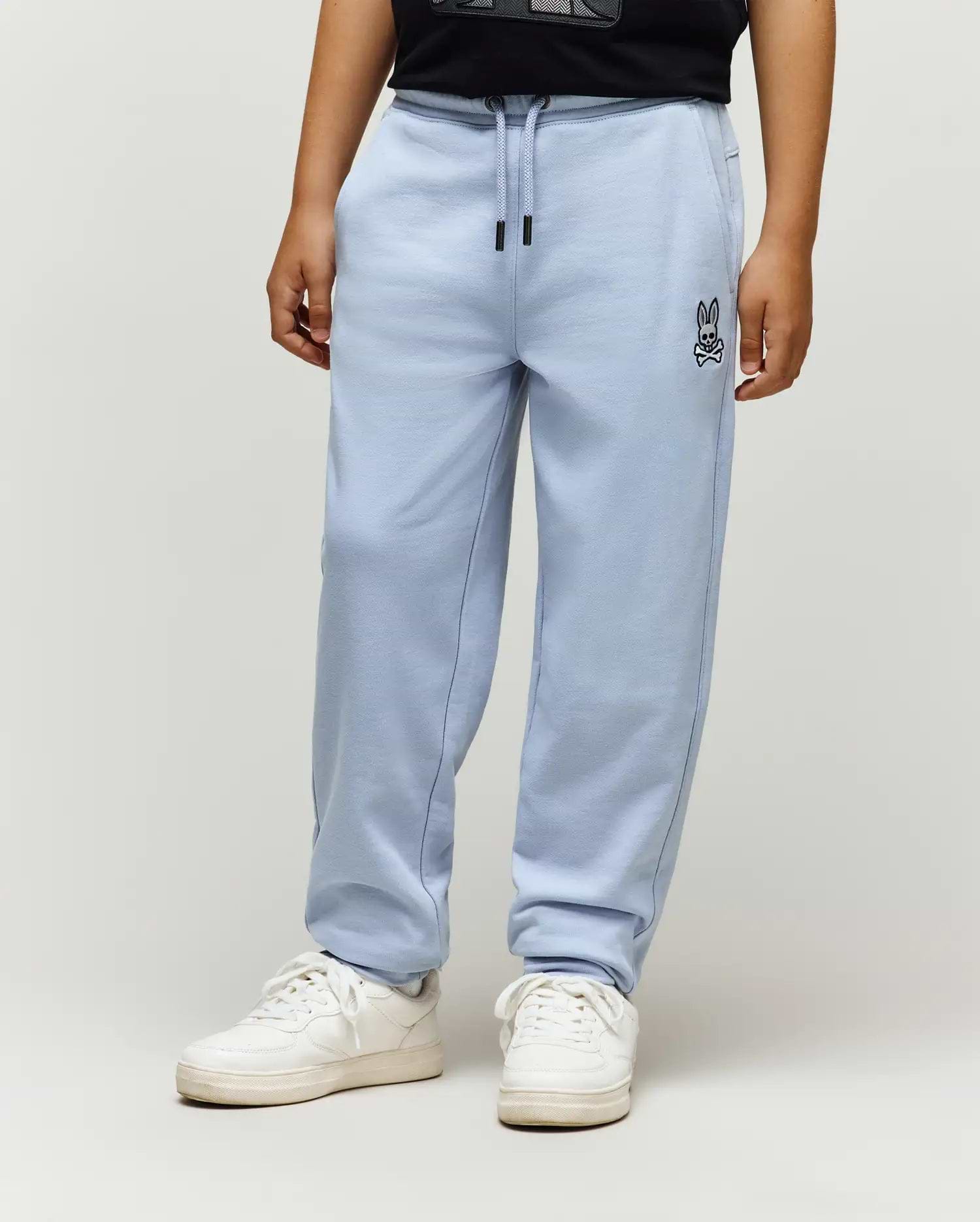 Kids Timothy 4K Bunny Jogger in light blue, a relaxed fit french terry jogger with an embroidered black Psycho Bunny skull logo on the left thigh and black drawstring tips.