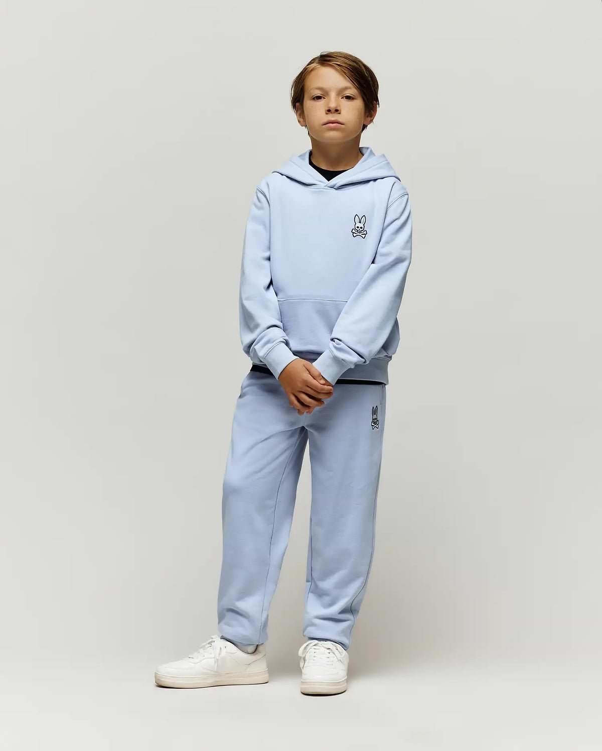 Light blue Kids Timothy 4k Bunny Jogger set, featuring a relaxed fit French terry hoodie with kangaroo pocket and matching joggers, both with small embroidered black Psycho Bunny skull logos.