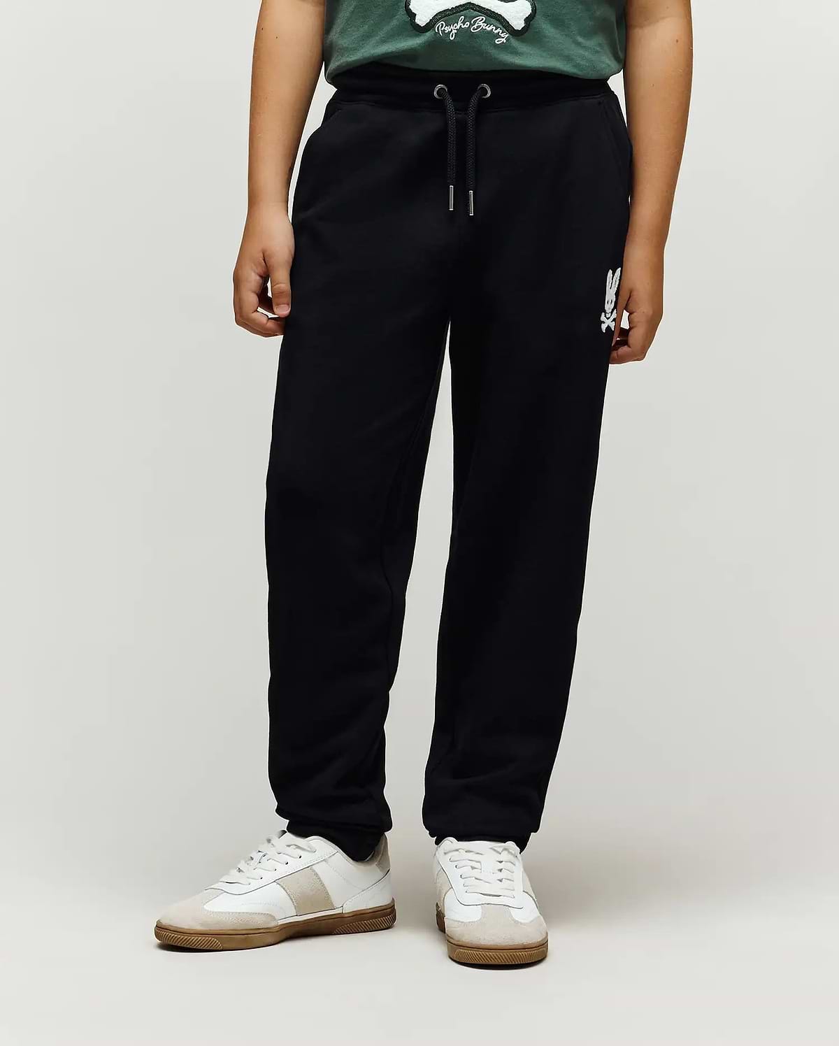 Kids Tate Chenille Sweatpant in black french terry, featuring a relaxed fit, drawstring waist, and a white chenille Psycho Bunny skull logo on the right thigh.