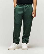 Kids Tate Chenille Sweatpant in dark green, a relaxed fit with drawstring waist, cuffed ankles, and a small embroidered black Psycho Bunny skull logo on the upper right thigh, featuring subtle ribbed side panels.