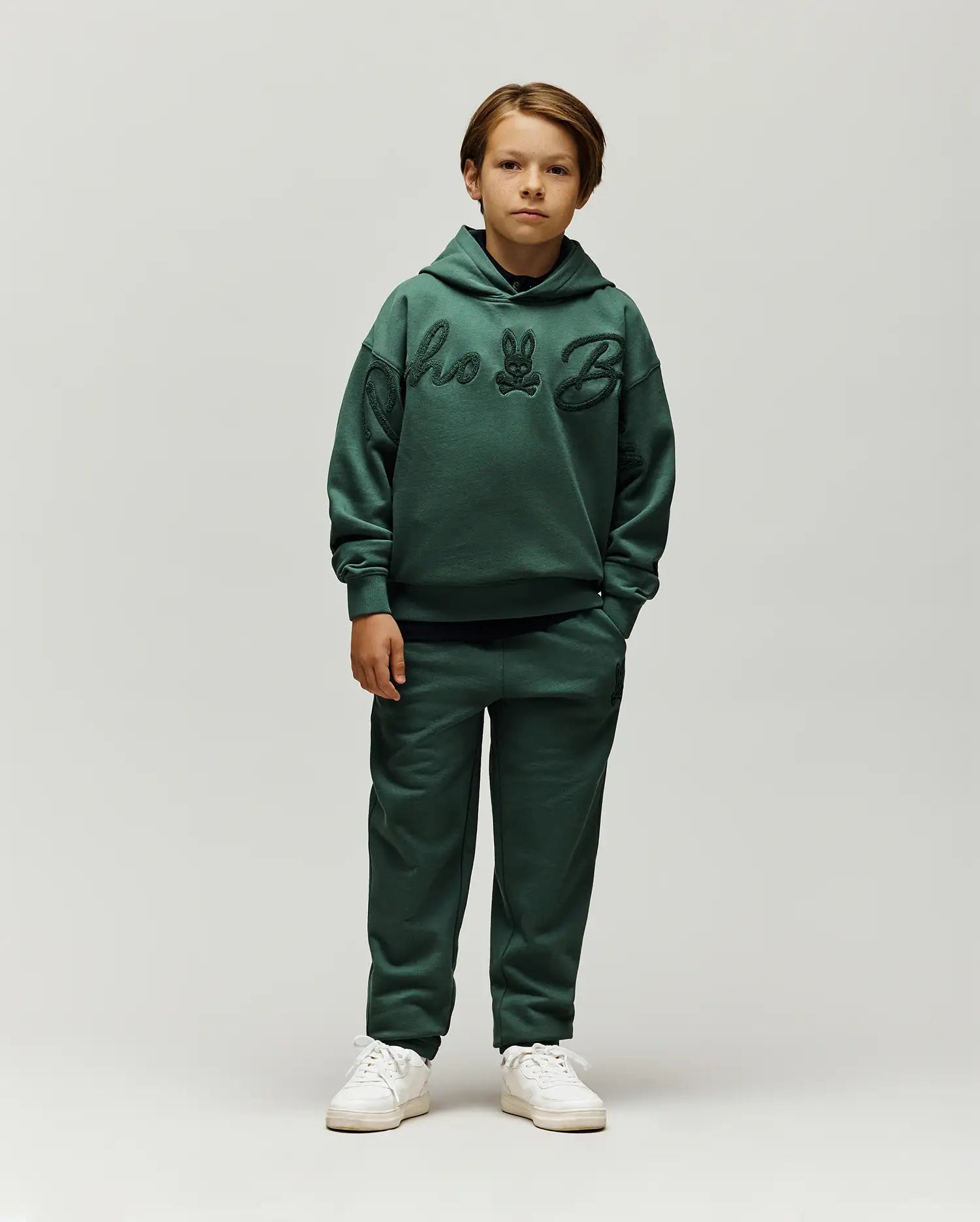 Forest green relaxed fit french terry hoodie with large tonal chenille Psycho Bunny script and skull logo on chest, paired with Kids Tate Chenille Sweatpant featuring a small tonal bunny skull logo.