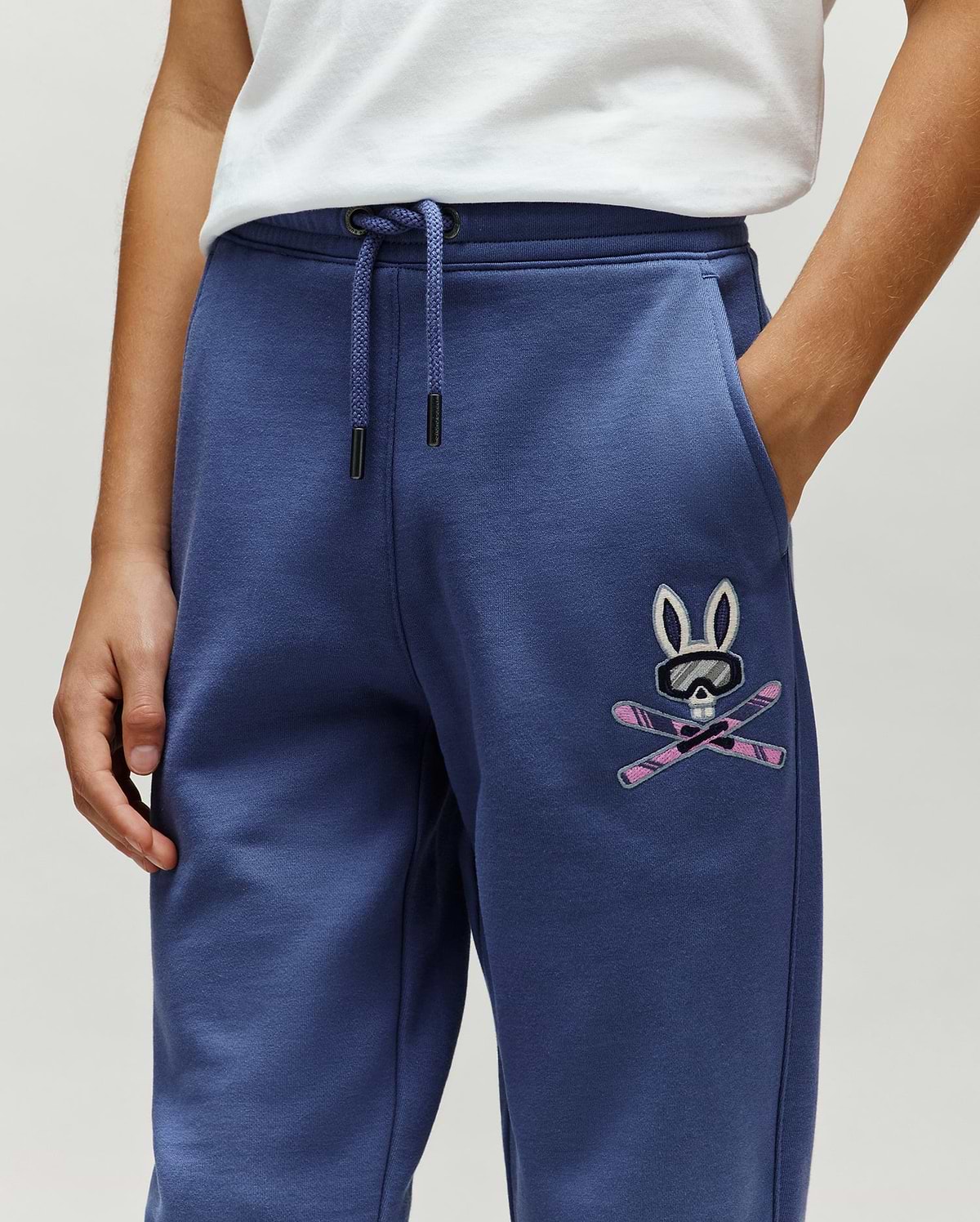 Kids Indigo Ski Bunny Sweatpant, relaxed fit, made from soft french terry, features a medium-sized embroidered Psycho Bunny skull with ski goggles and crossed pink skis on the left thigh.