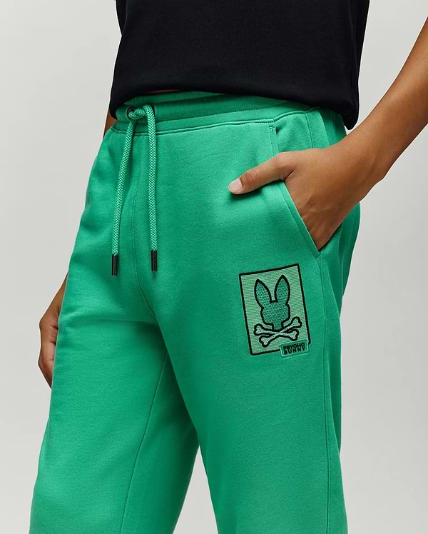 Bright Green Kids Varen Jogger in soft french terry, featuring a relaxed fit, drawstring waist with black metal tips, and a large embroidered black-outlined Psycho Bunny skull logo patch on the left thigh.
