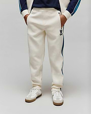 Kids Caspian Contrast Stripe Track Pant in cream french terry, featuring a relaxed fit, dark blue side stripe, and a small embroidered Psycho Bunny skull logo on the left thigh.