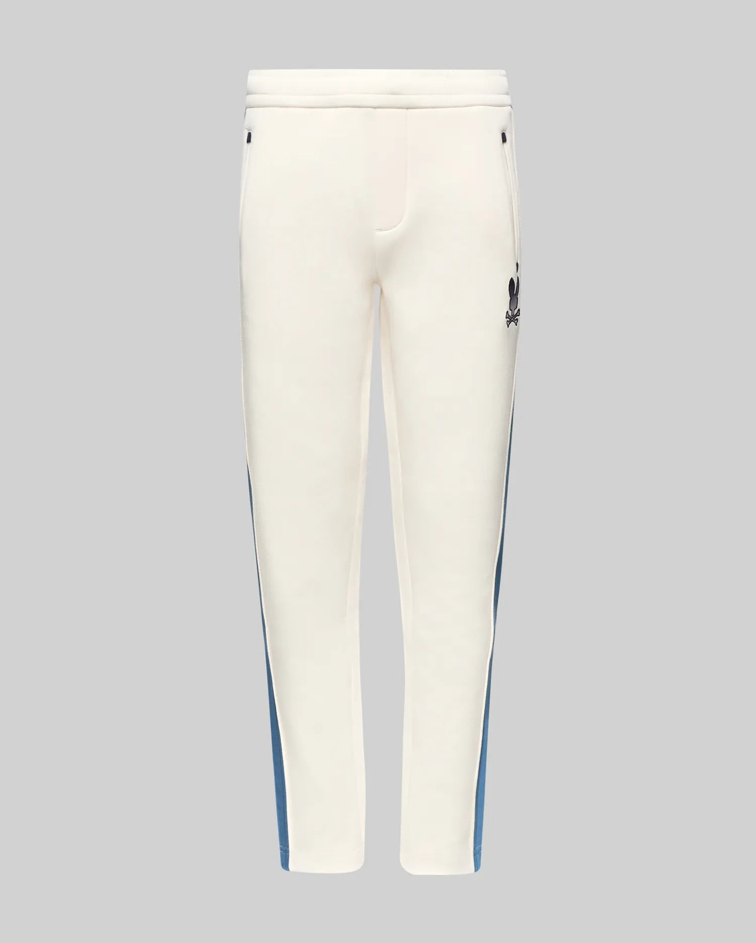 Kids Caspian Contrast Stripe Track Pant in cream, featuring a blue side stripe, relaxed fit, smooth fabric, and a small black embroidered Psycho Bunny skull logo on the upper right thigh.