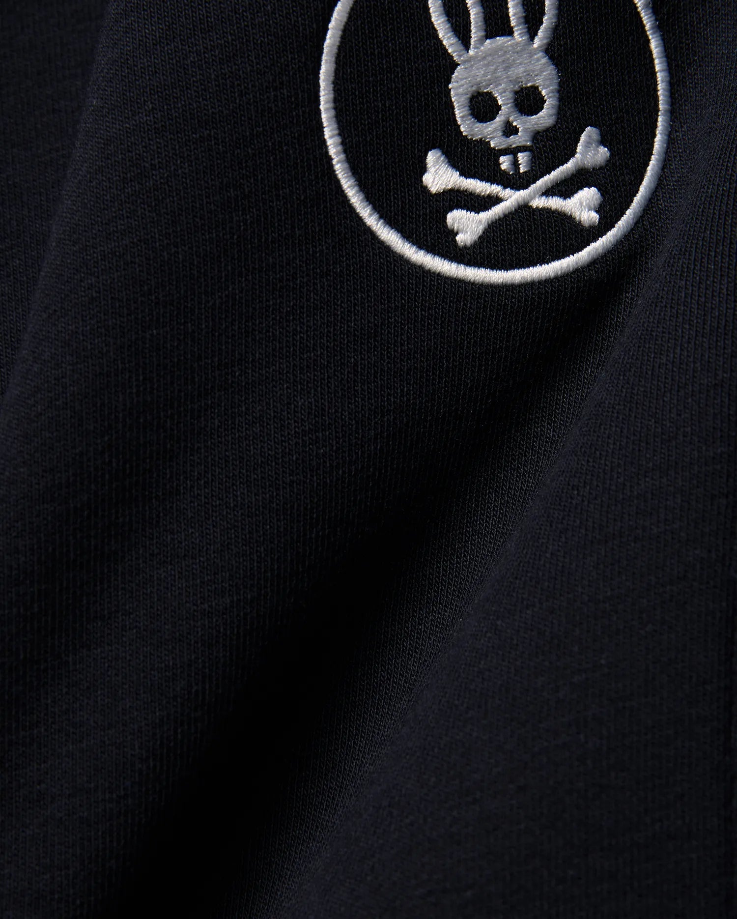 Kids Nathaniel Sweatpant in deep navy blue, crafted from soft jersey knit fabric, featuring a prominent white embroidered Psycho Bunny skull and crossbones logo.