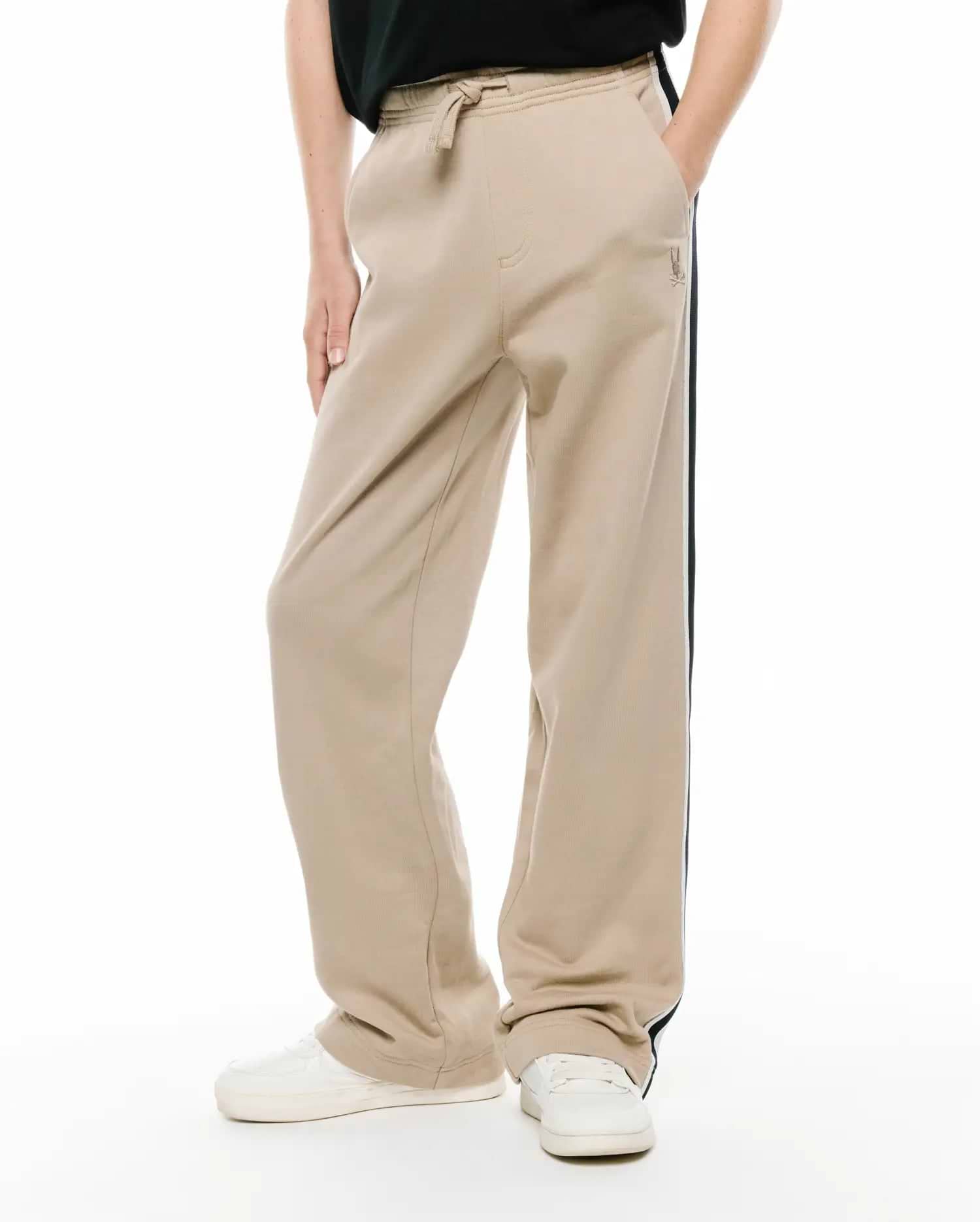 Kids Ty French Terry Sweatpant, beige relaxed fit with drawstring waist, side pockets, dark blue and white side stripe, and small embroidered Psycho Bunny logo.