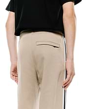 Kids Ty French Terry Sweatpant in beige, featuring a relaxed fit, soft french terry fabric, a back welt pocket, and a distinctive navy and white side stripe.