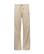 Kids Ty French Terry Sweatpant in beige, featuring a relaxed fit, drawstring waist, navy and white side stripes, and a small embroidered Psycho Bunny skull logo on the upper right thigh.