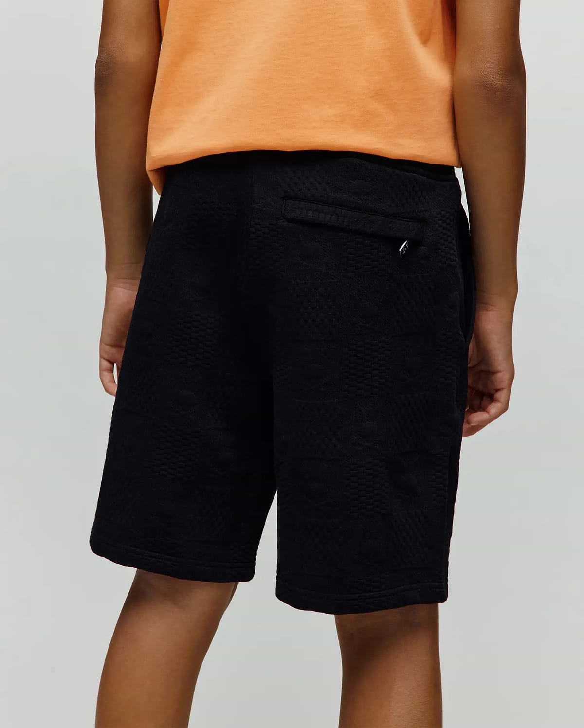 Kids Dustin Sweatshort, black relaxed fit with a subtle geometric textured jacquard knit pattern and a small silver Psycho Bunny logo tag on the back pocket.