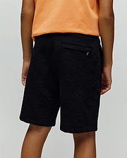 Kids Dustin Sweatshort, black relaxed fit with a subtle geometric textured jacquard knit pattern and a small silver Psycho Bunny logo tag on the back pocket.