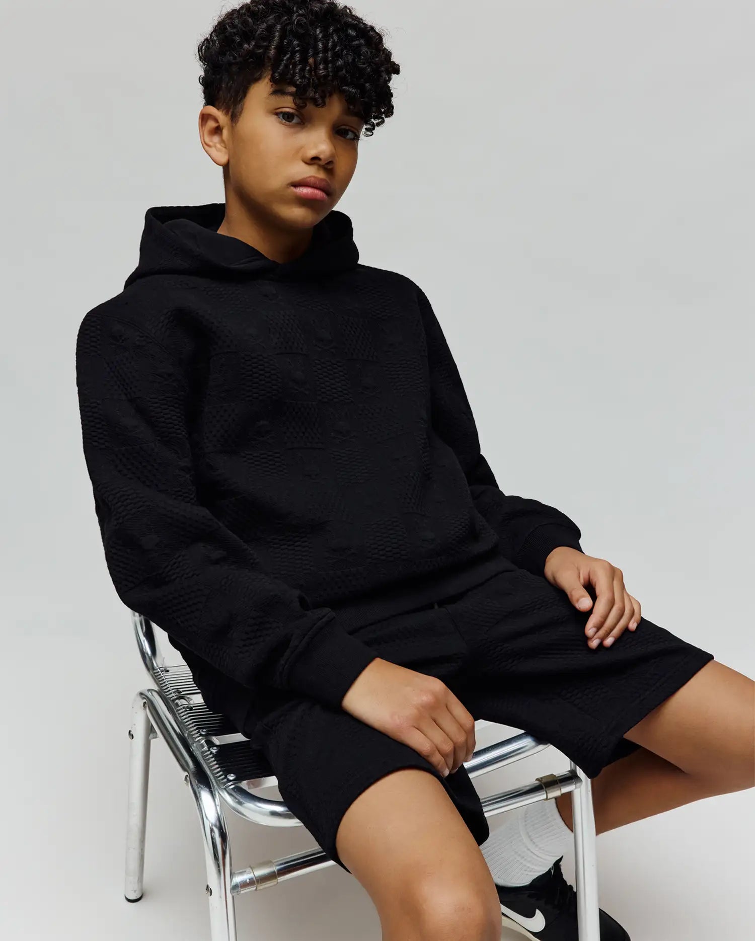 Black relaxed fit hoodie and Kids Dustin Sweatshort set, featuring an all-over subtle embossed Psycho Bunny skull logo pattern on textured knit fabric.