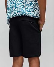 Kids Barry Modal Short in black, offering a relaxed fit with a subtle metal Psycho Bunny logo on the back pocket, complemented by a white and teal pixelated bunny skull pattern shirt.