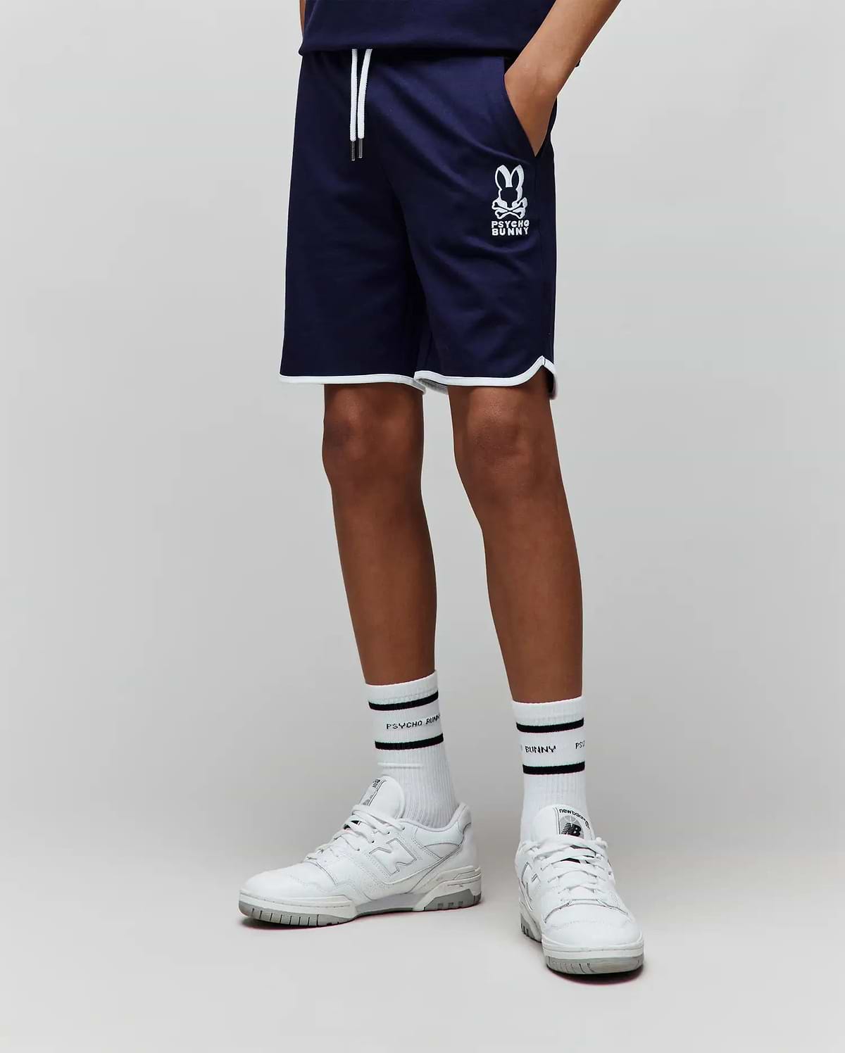 Kids Toby Short, navy smooth knit with a relaxed fit, featuring white piping on the hem, white drawstrings, and a medium-sized white printed Psycho Bunny skull logo on the left thigh.
