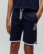 Kids Toby Short, navy French terry shorts with a relaxed fit, featuring white drawstrings, a large embroidered Psycho Bunny skull logo on the left leg, and white piping on the curved hem.